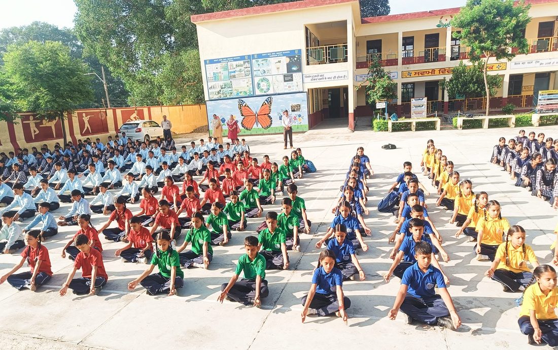Students seated in the school ground during a yoga session